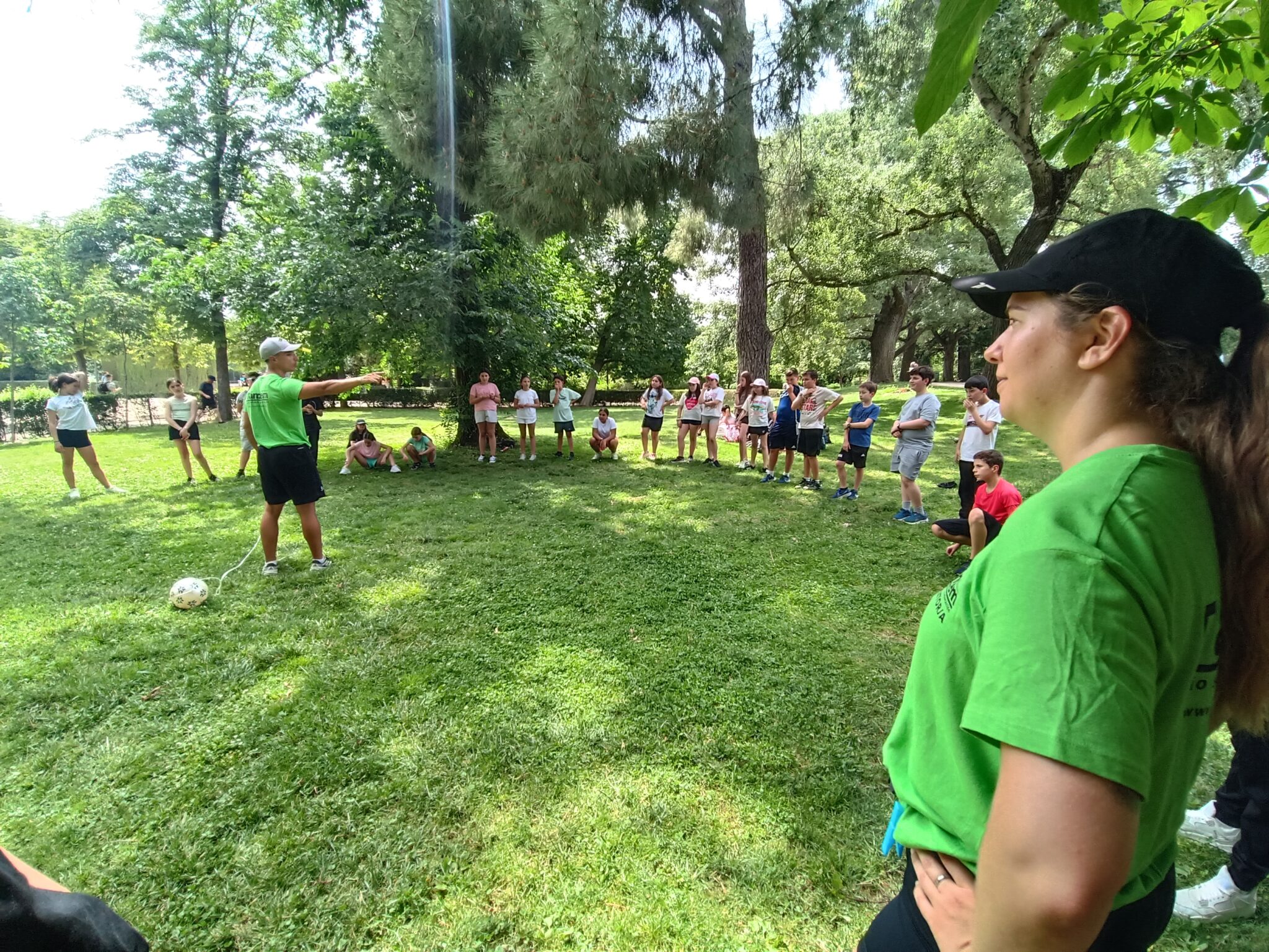 dos monitores guiando un juego en un parque con un grupo de primaria