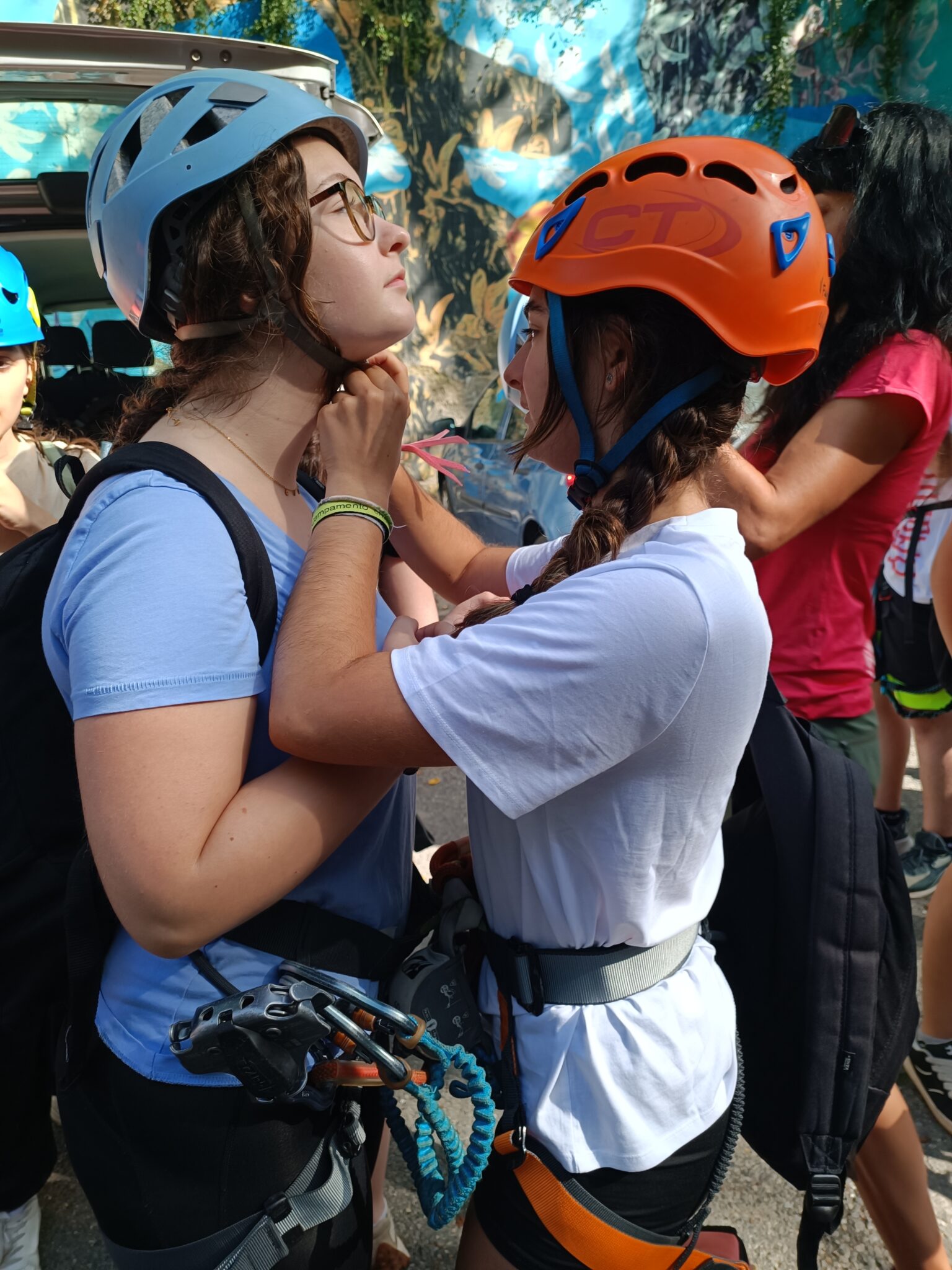 dos amigas adolescentes ayudándose a ponerse el casco de escalada