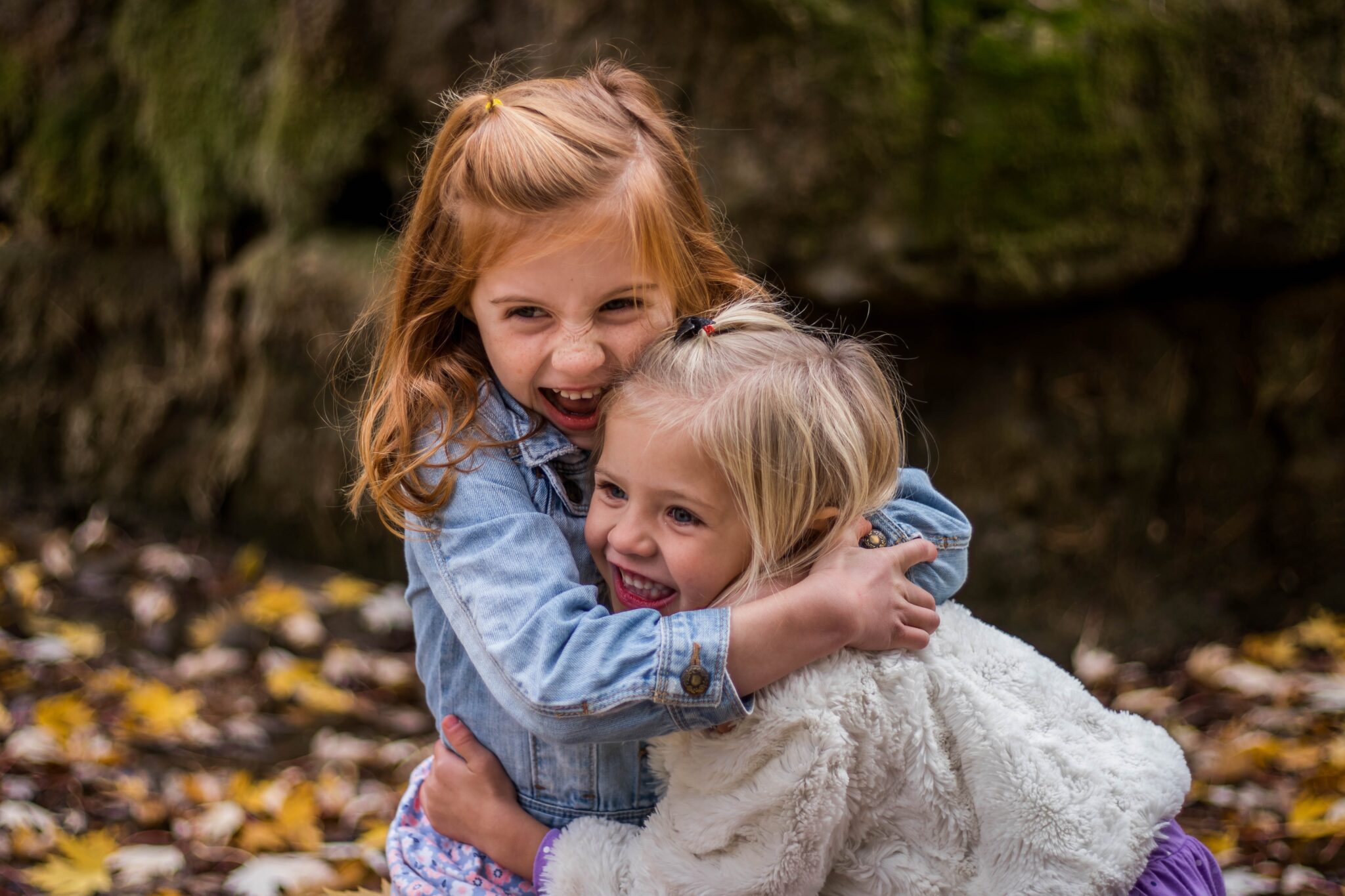 dos niñas abrazándose y riendo en otoño