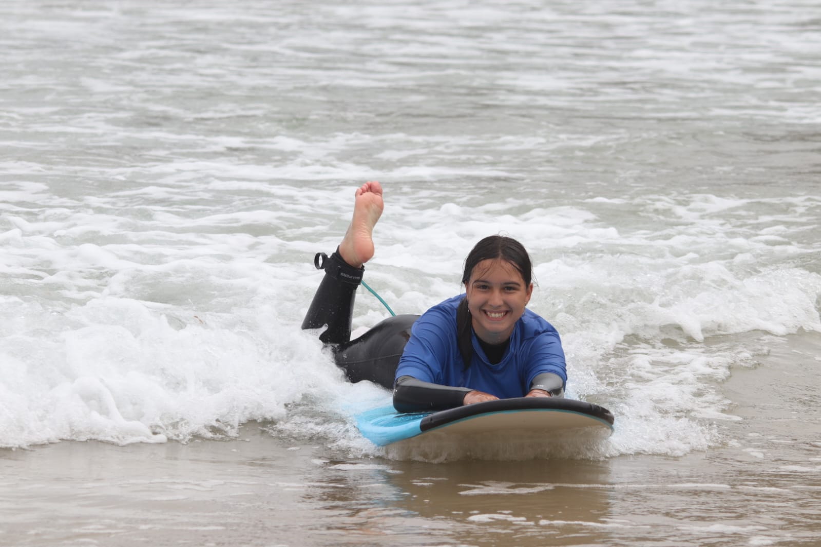 chica de primaria sonriente sobre una tabla de surf