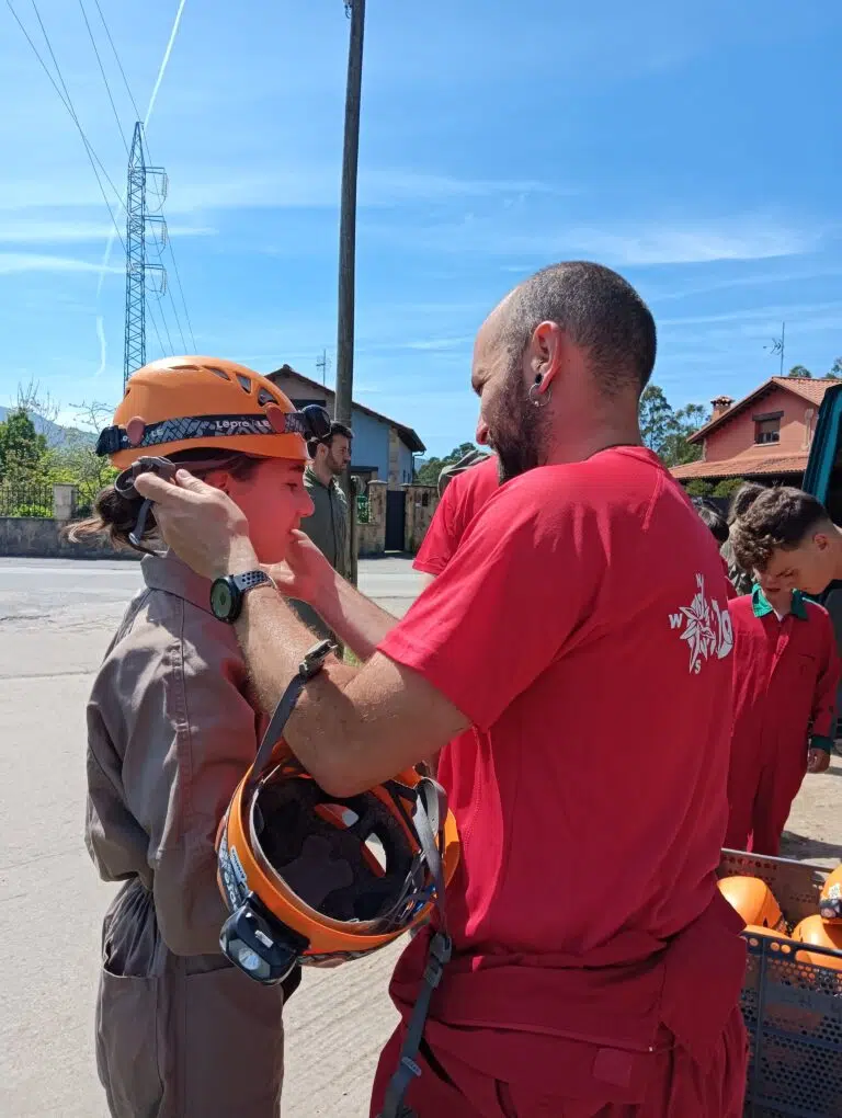 monitor vestido de rojo colocando un casco a una niñoa