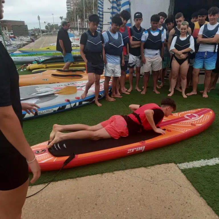 Un alumno realizando una practica en tierra de como ponerse en la tabla de paddle surf