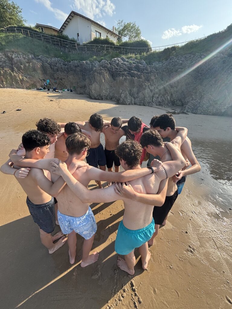grupo de secundaria de chavales abrazados en la playa