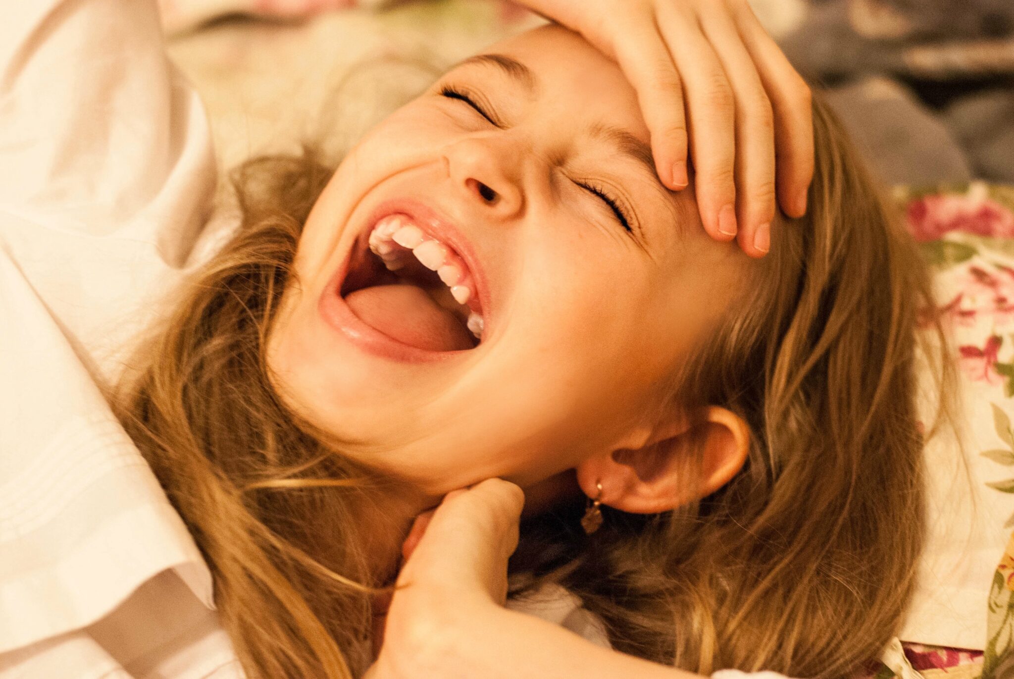 primer plano de una niña que se ríe con la boca abierta y los ojos cerrados