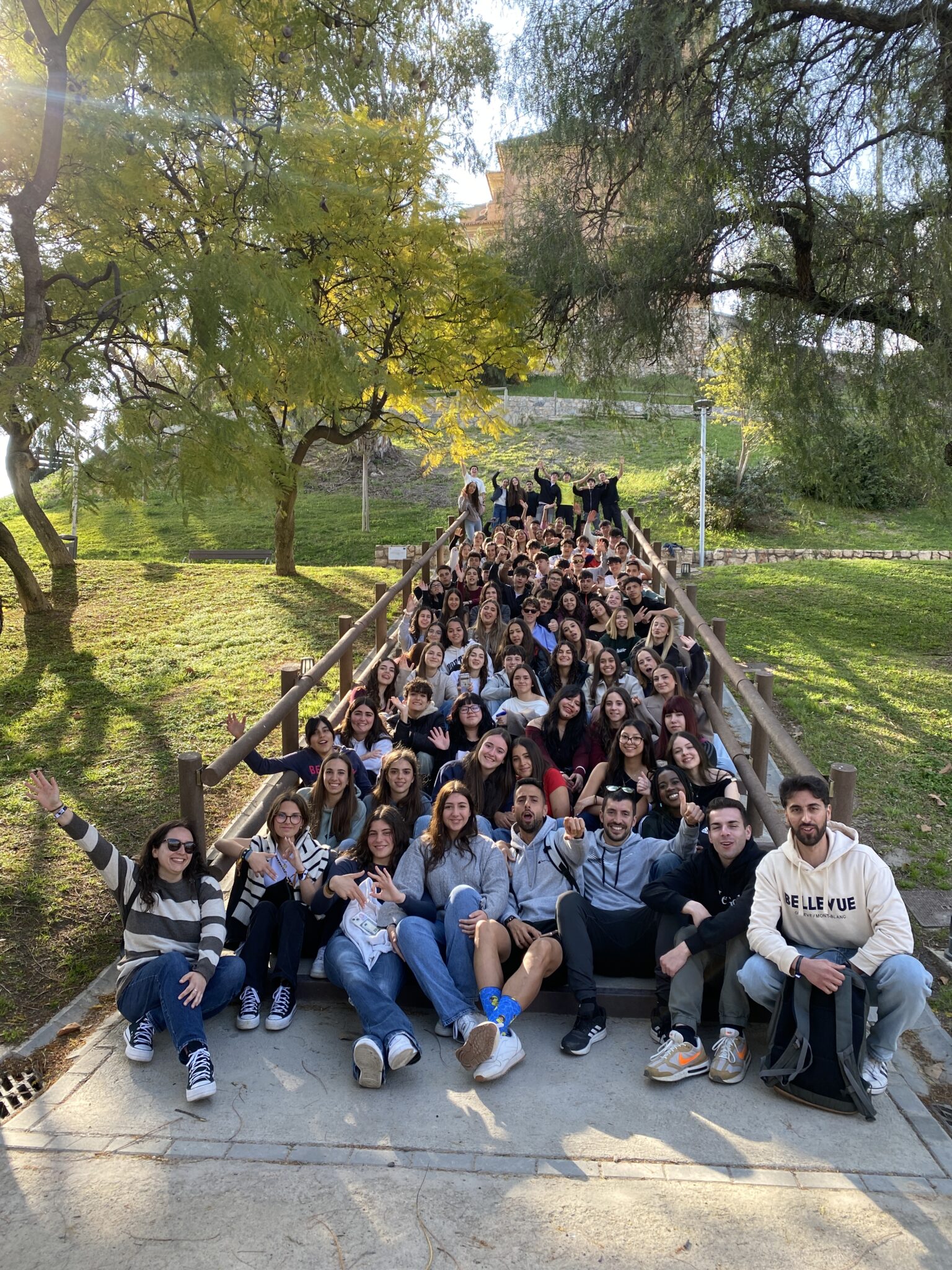 Grupo de secundaria sentados en las escaleras de un parque con sus profesores y monitores