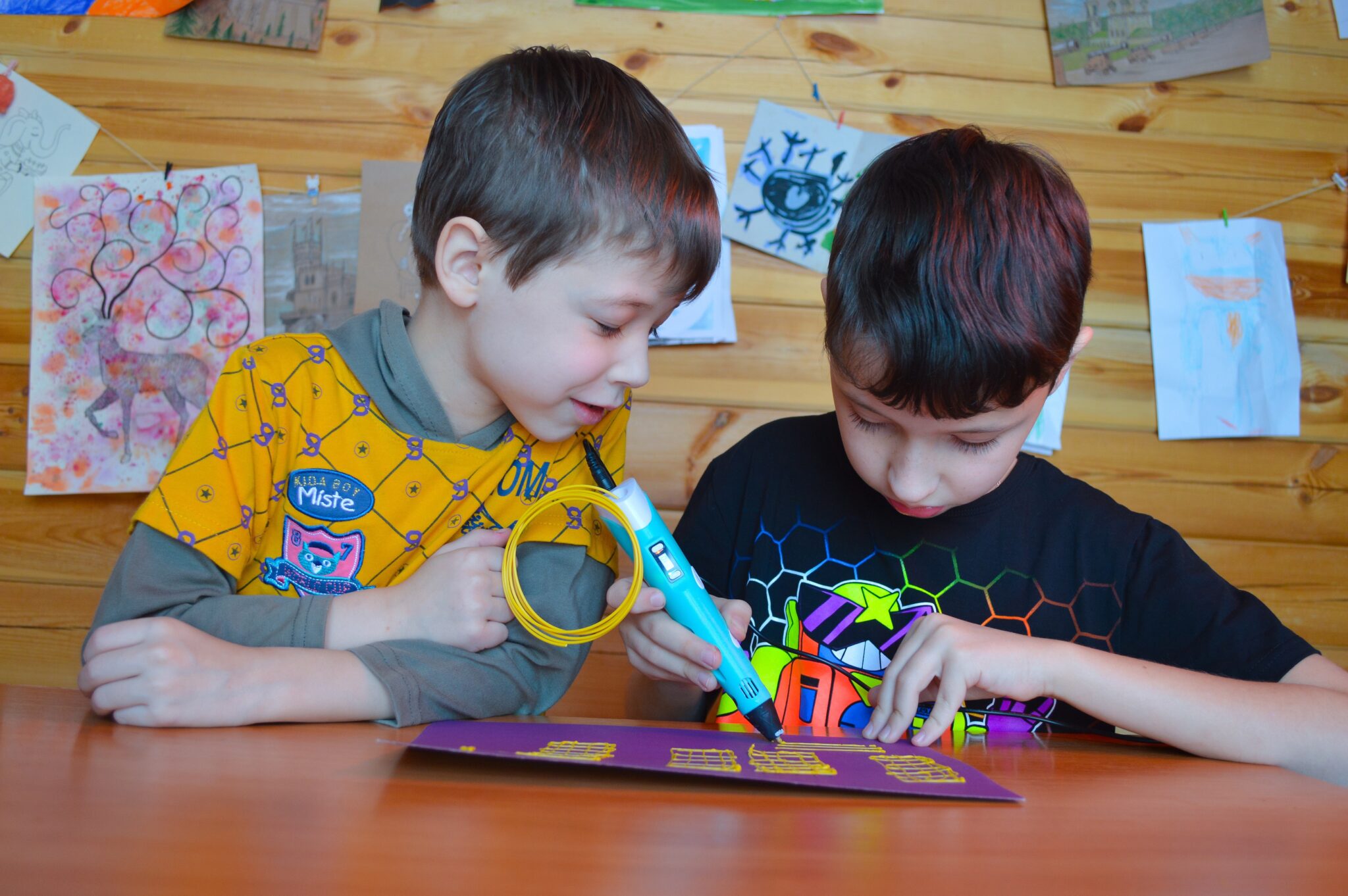 dos niños con un boligrafo impresora 3d dibujando cuadriculas