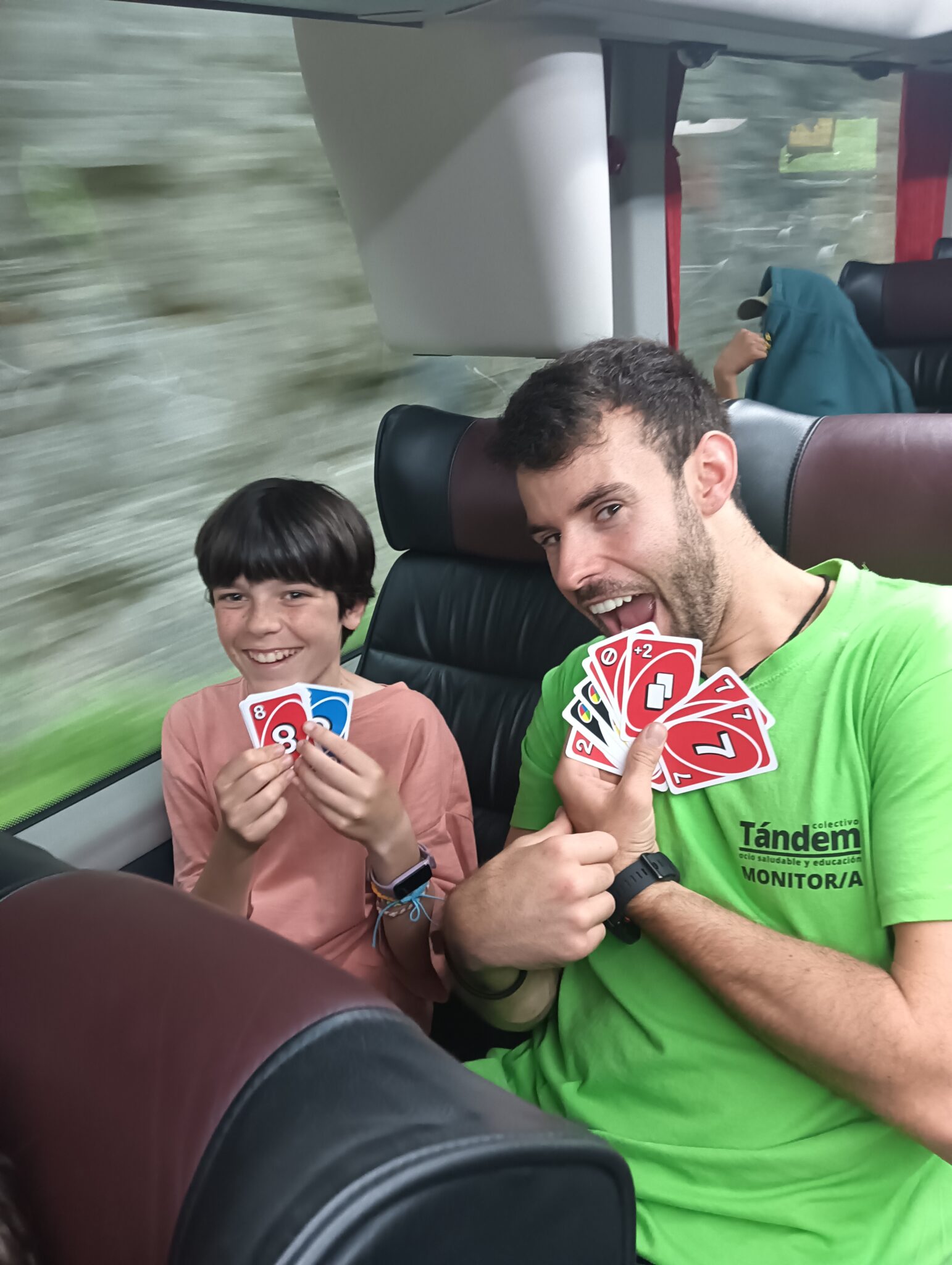 En un autocar un monitor juega con un participante al juego de carta "uno"