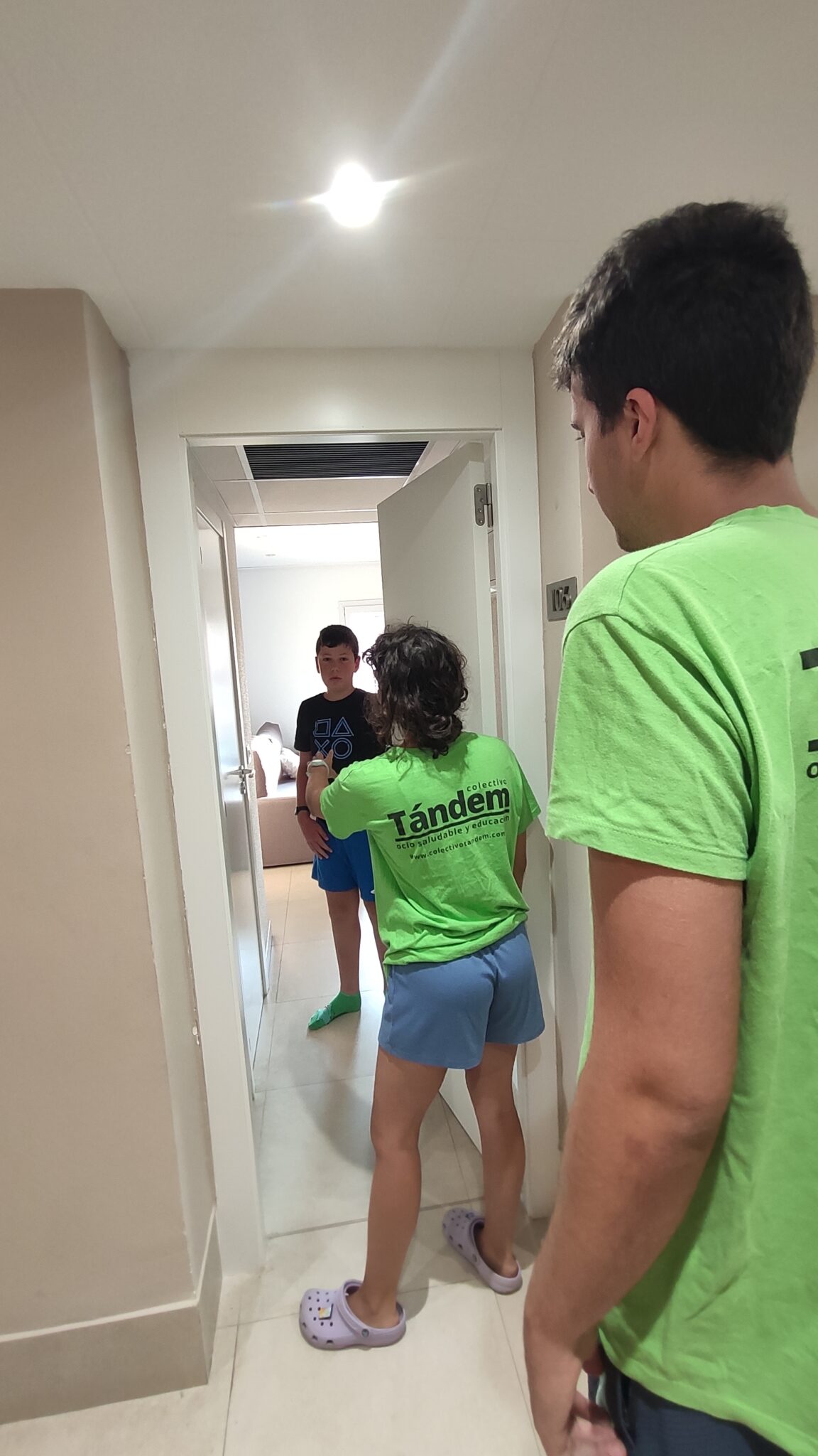 Dos monitores de Colectivo Tándem dando instrucciones a un chaval en la puerta de su habitación