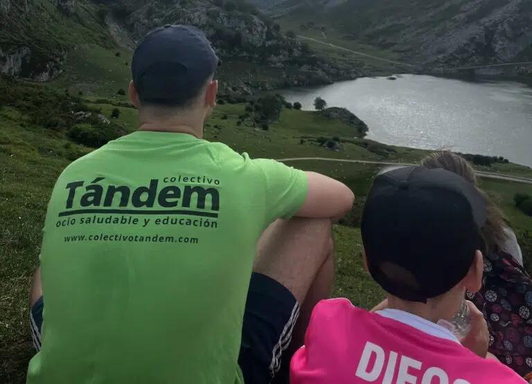 con los lagos de covadonga de fondo, un monitor y un chaval de espaladas contemplándolos