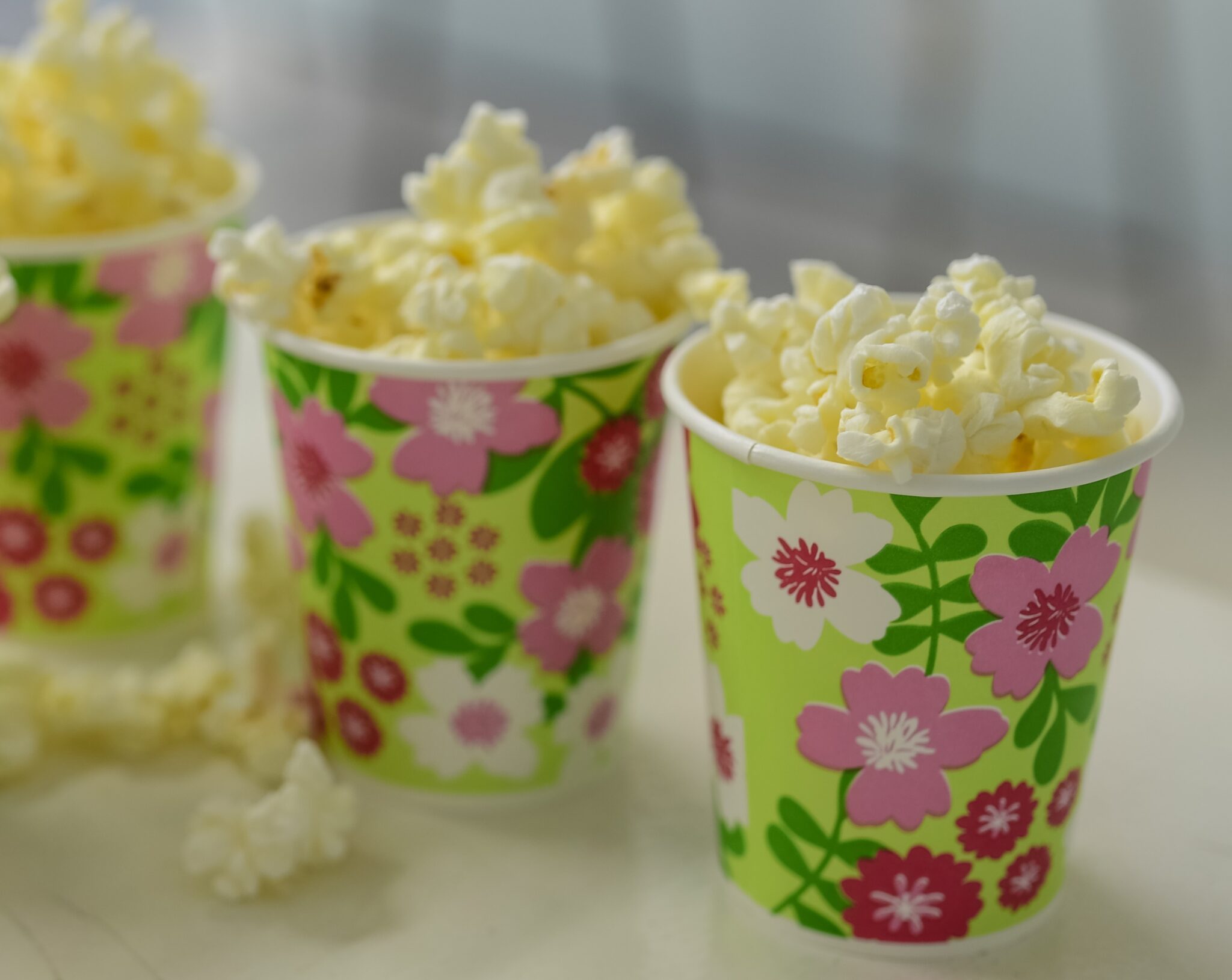 3 vasos de carton de flores de colores que contienen palomitas
