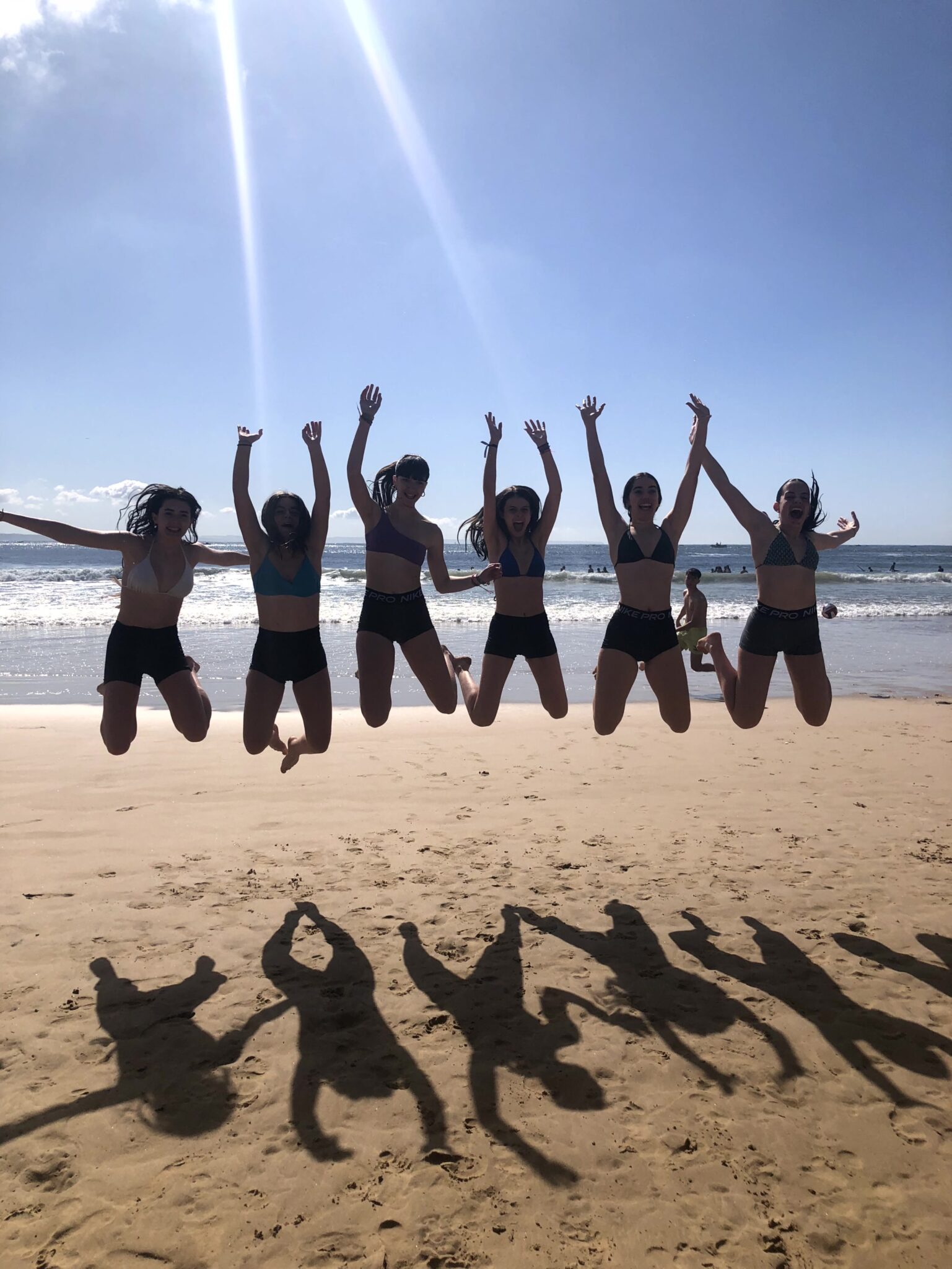 seis chicas que saltan con la playa de fondo