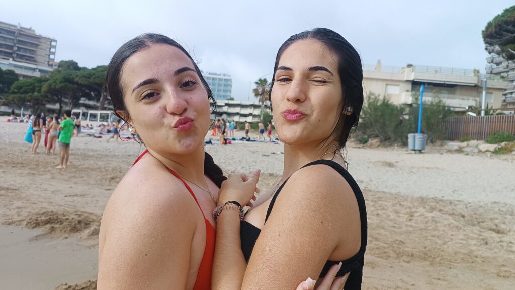 Primer plano de dos adolescentes recién salidas del agua en la playa que lanzan un beso a camara