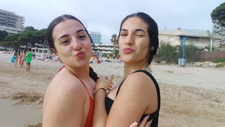 Primer plano de dos adolescentes recién salidas del agua en la playa que lanzan un beso a camara