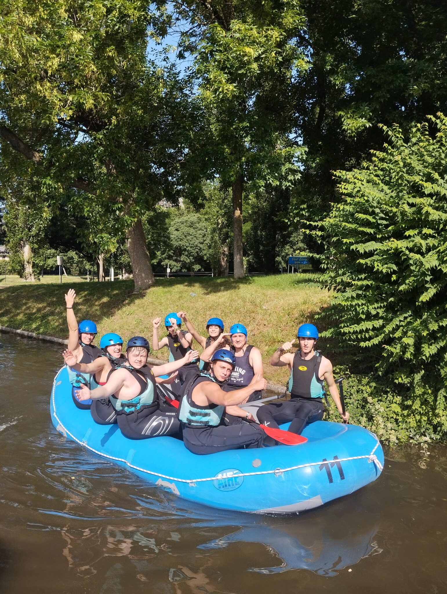 Grupo de secundaria subidos en una canoa de rafting con cascos azules