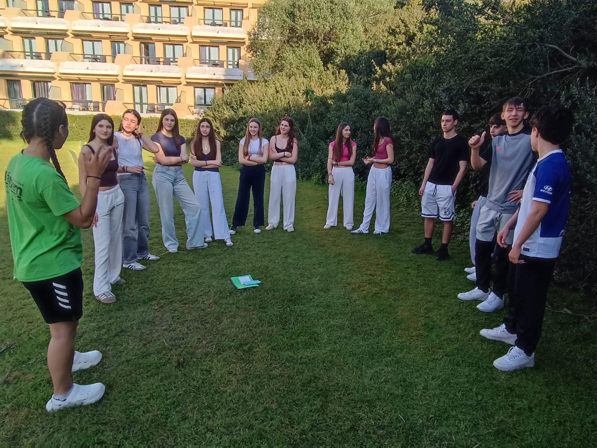 grupo de adolescentes escuchando a su monitora en el jardín de un hotel
