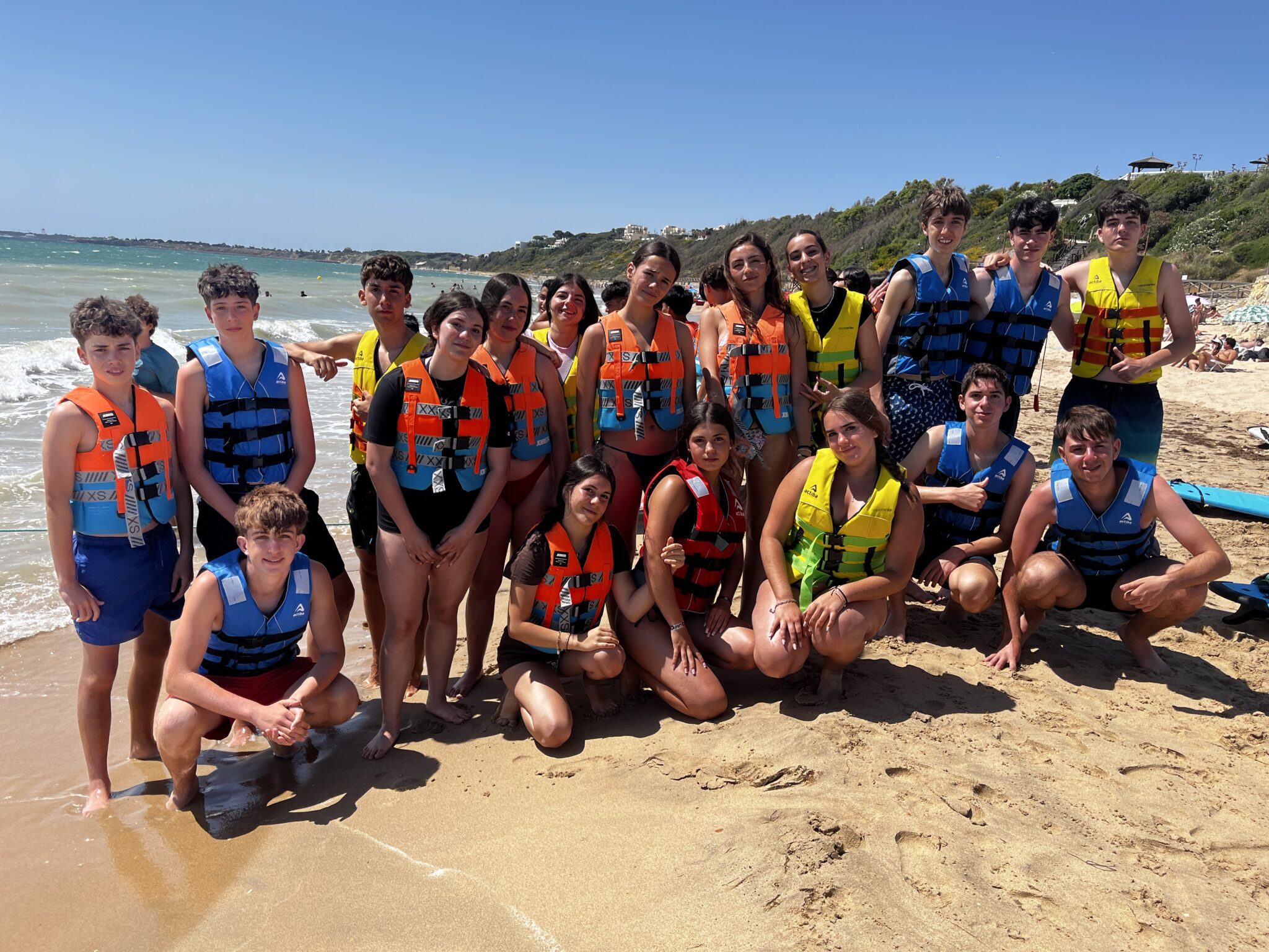Grupo de secundaria en la playa posando con los chalecos salvavidas