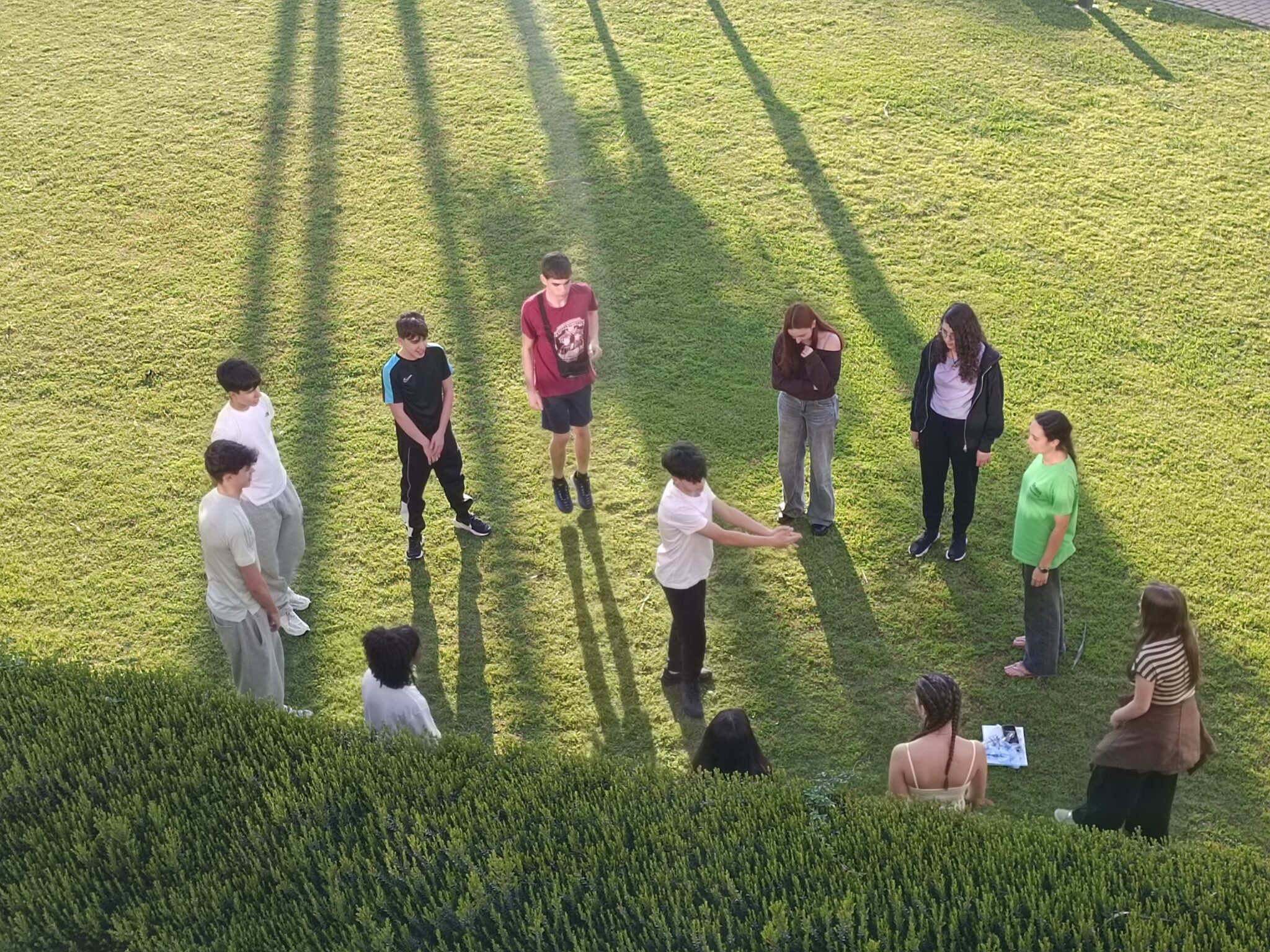 Grupo de secundaria jugando en circulo en el jardín de un hotel