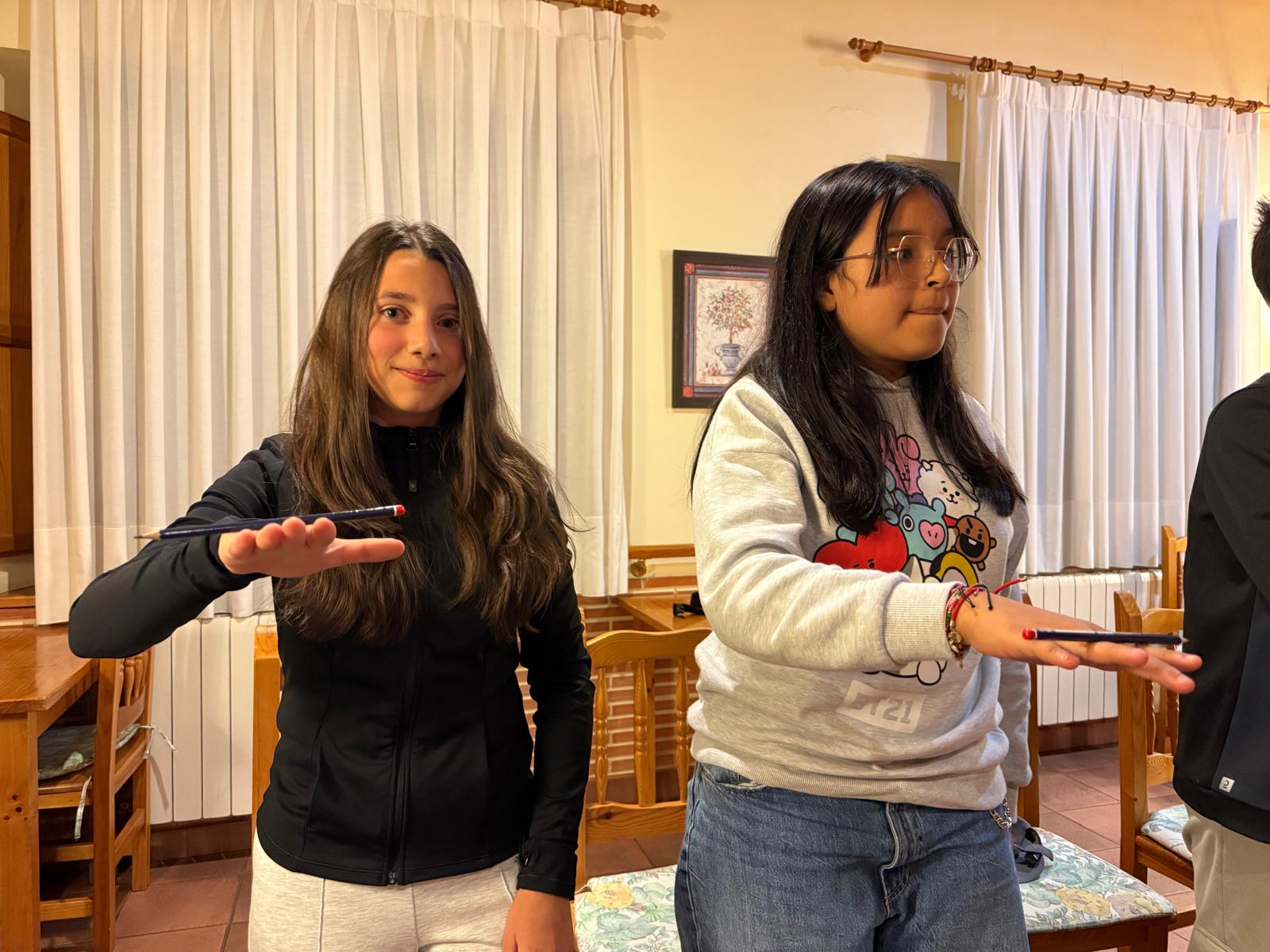 dos chicas de primaria jugando con un lápiz en la mano