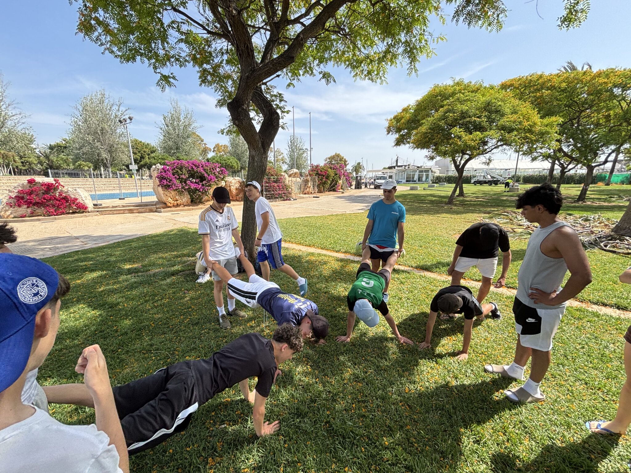 grupo de secundaria en un parque haciendo carretillas por parejas