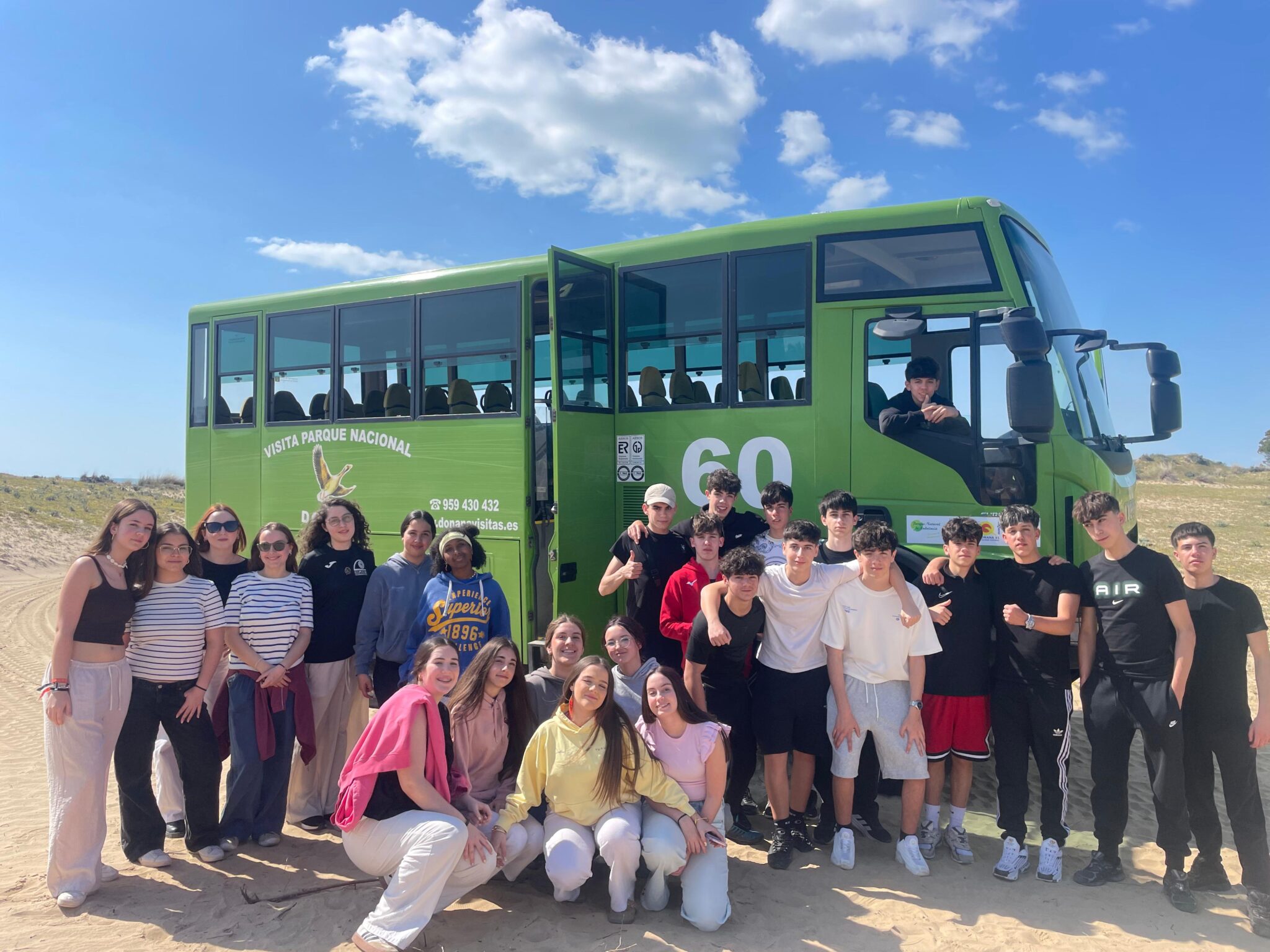grupo de secundaria en las dunas de Doñana delante de un autocar verde 4x4