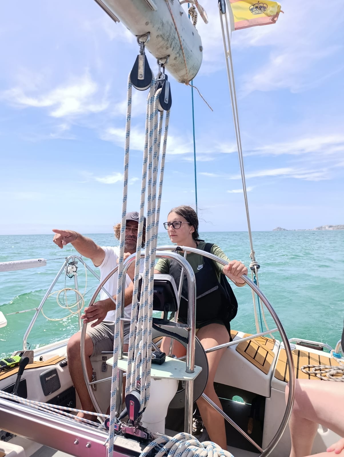 monitor de vela dando instrucciones a una adolescente que lleva la embarcación