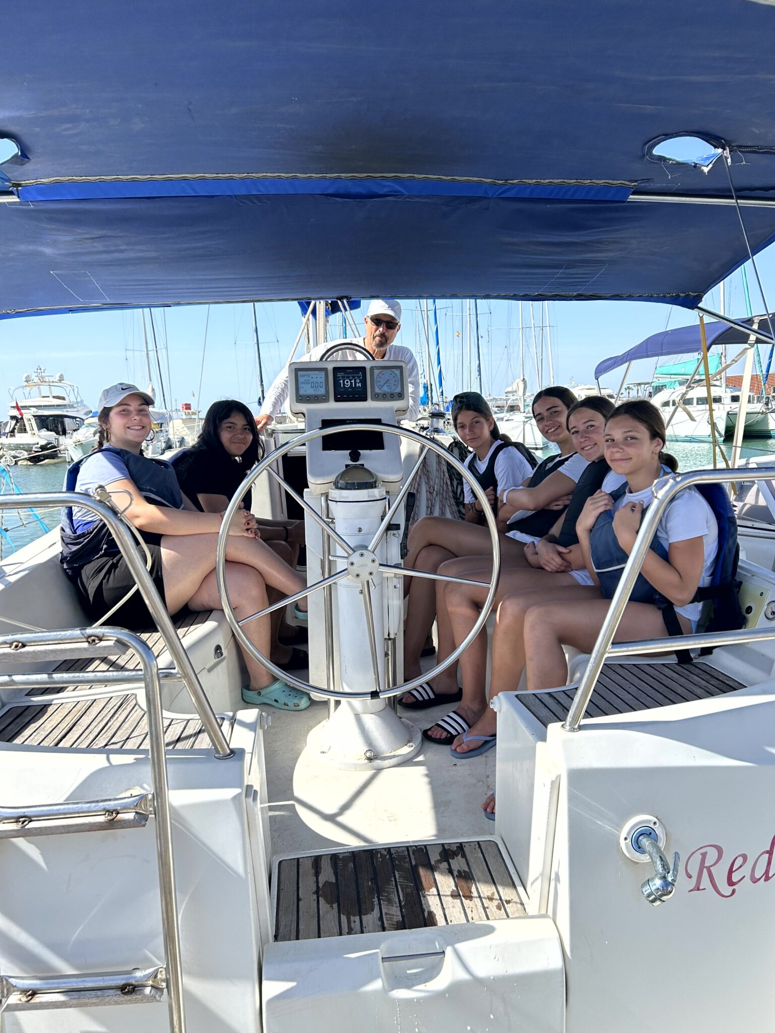 grupo de secundaria que está dentro de un barco de vela con toldo azul