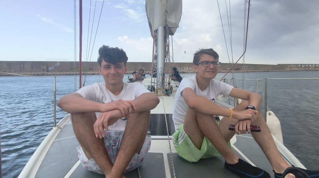 dos adolescentes sentados en un barco de vela