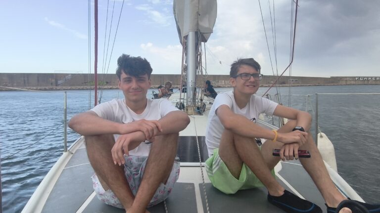 dos adolescentes sentados en un barco de vela