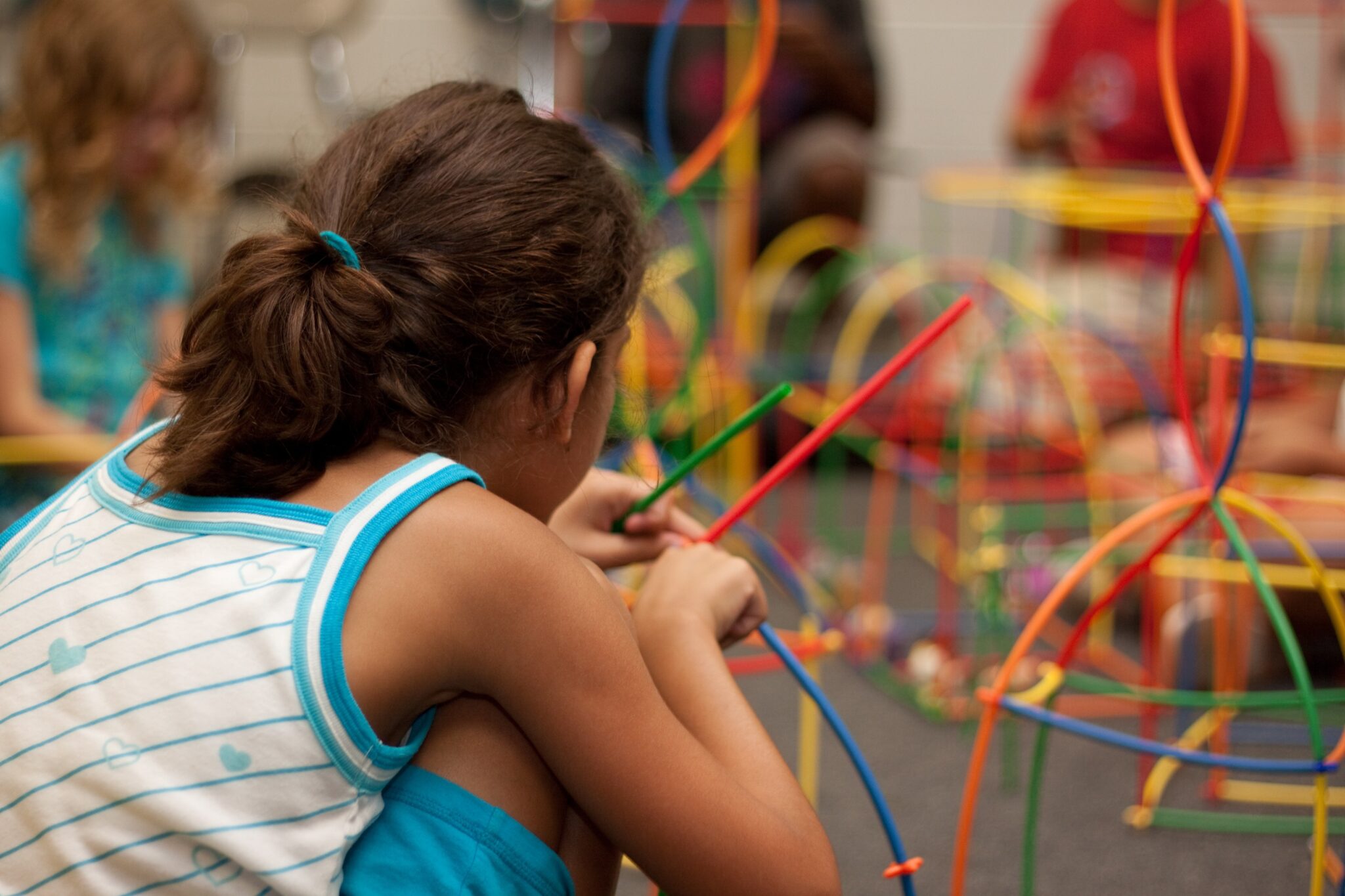niña de espaldas jugando con unas construcciones de colores