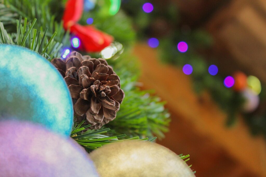 un detalle de un arbol de navidad donde se ve una piña y tres bolas