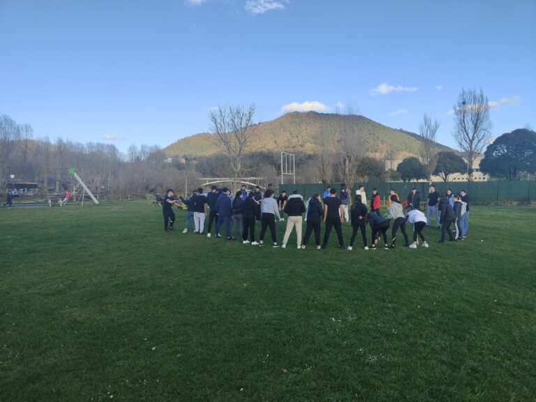 grupo de adolescentes en círculo en un parque haciendo una actividad
