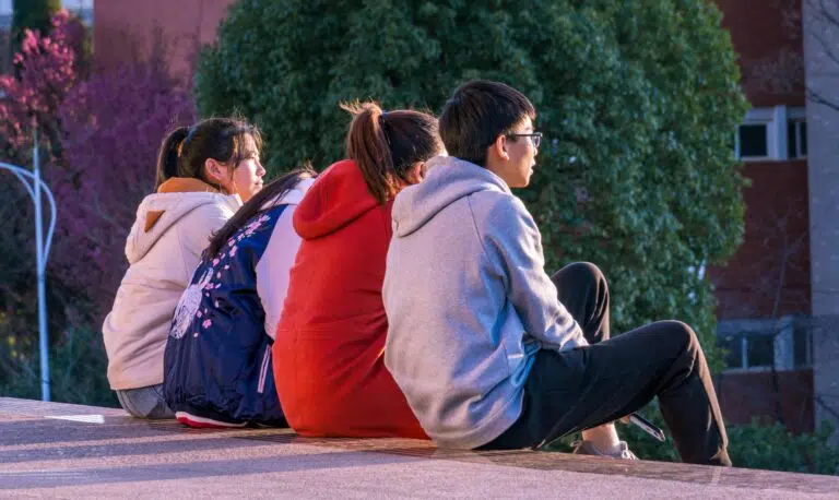 Cuatro adolescentes sentados de espaldas en unas escaleras