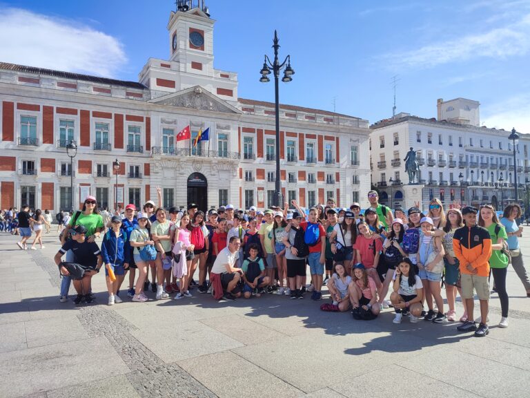 Puerta del sol de Madrid con el fondo el reloj y un grupo de primaria con monitores