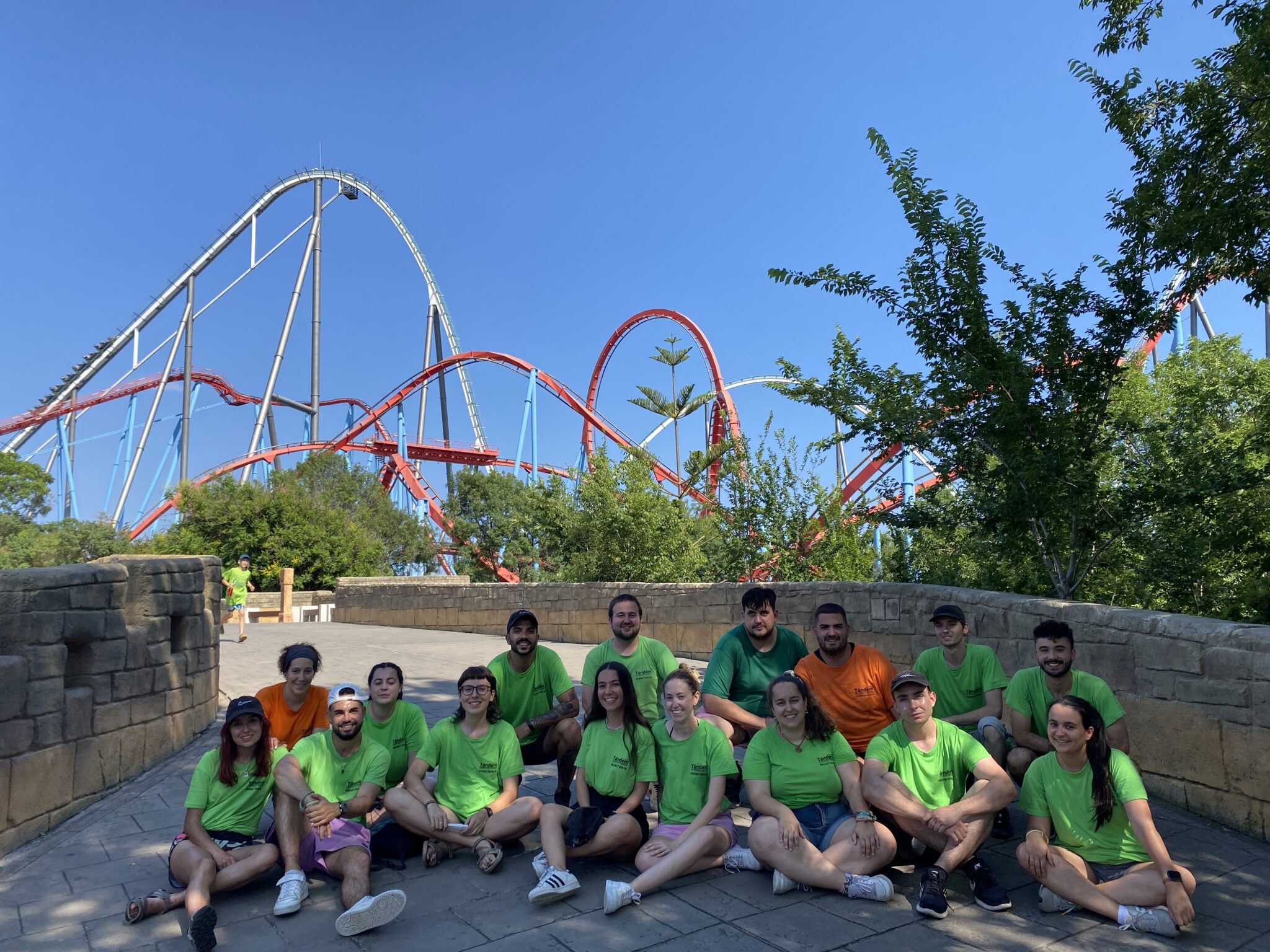 grupo de monitores y coordinadores de colectivo tandem con atracción de PortAventura al fondo