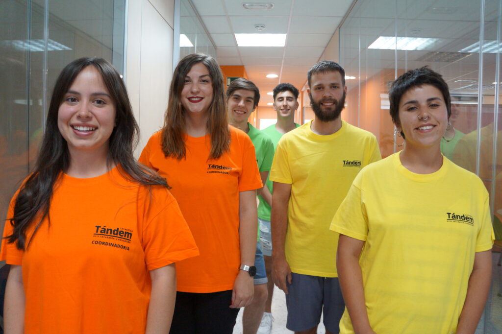 seis monitores de colectivo tandem en las oficinas muy sonrientes y con camisetas coorporativas