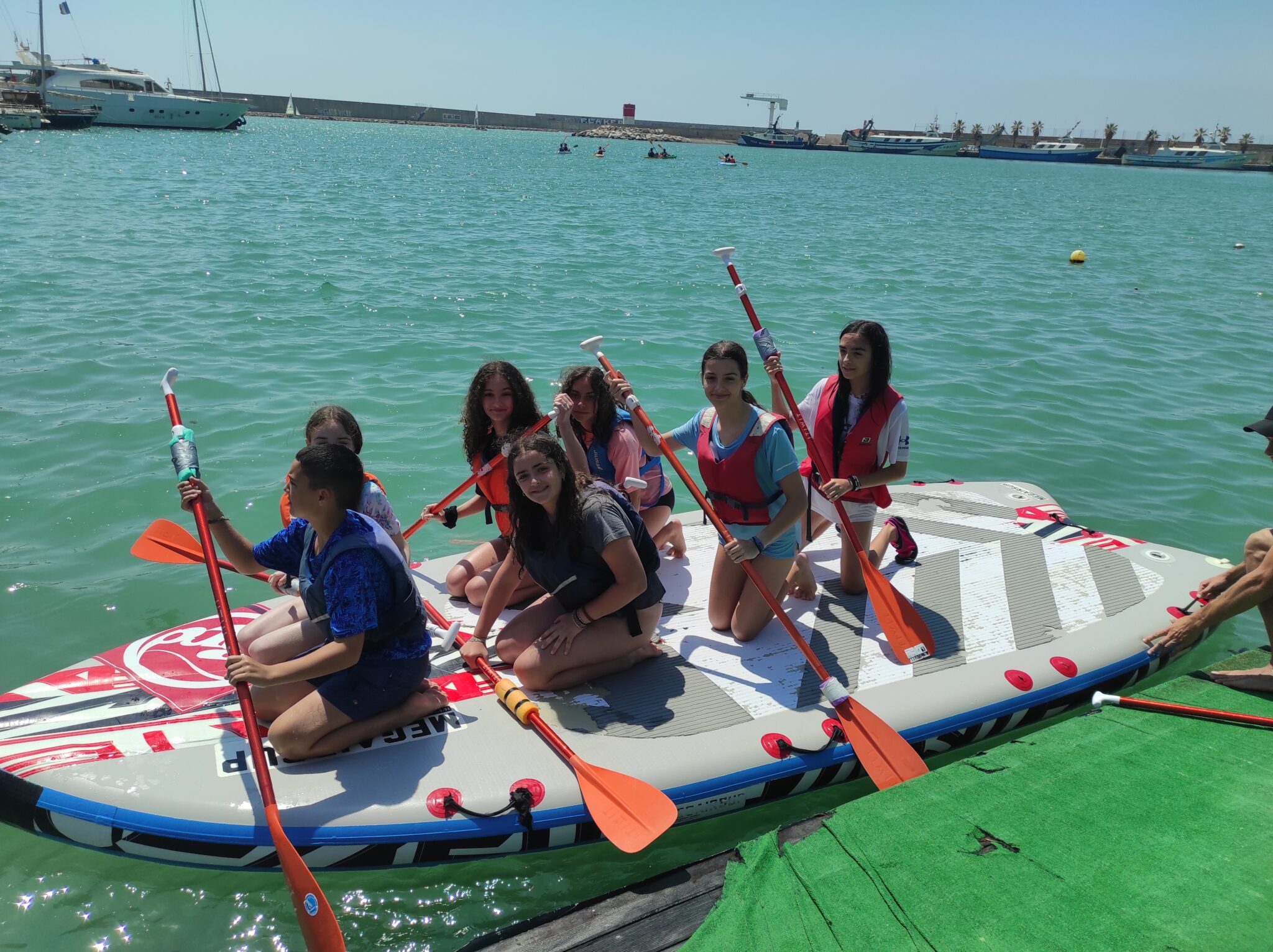 siete adolescentes de un viaje sobre una embarcación de paddel surf