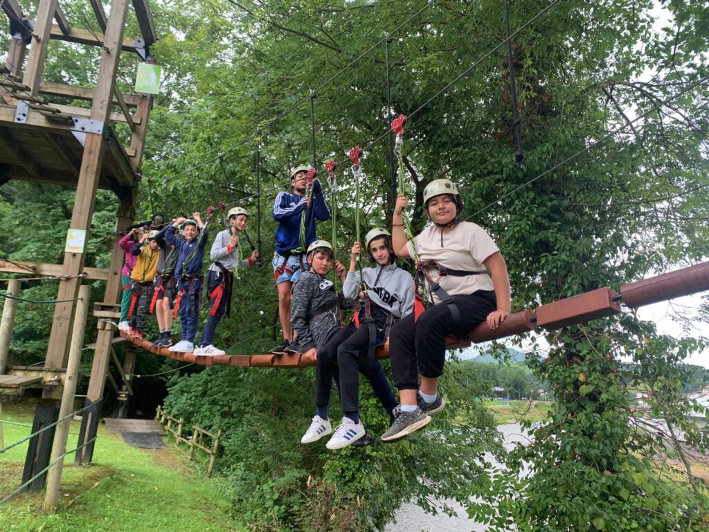 chavales de sexto de primaria subidos en un puente tibetano en arriondas, con cascos y arneses