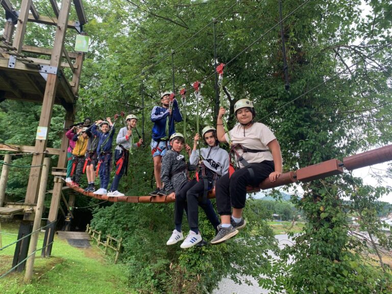 chavales de sexto de primaria subidos en un puente tibetano en arriondas, con cascos y arneses