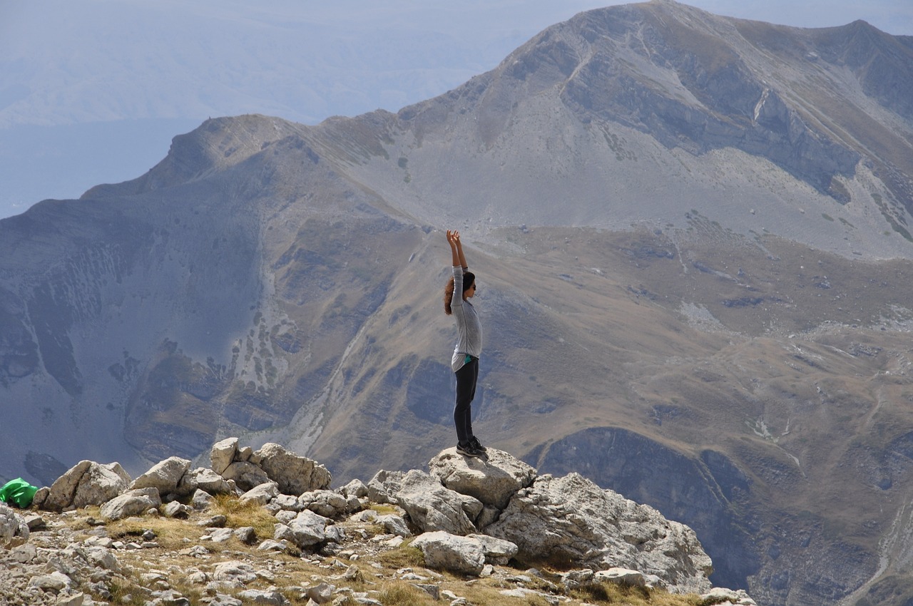 Mujer que ha subido una montaña y está disfrutando del paisaje con las brazos levantados