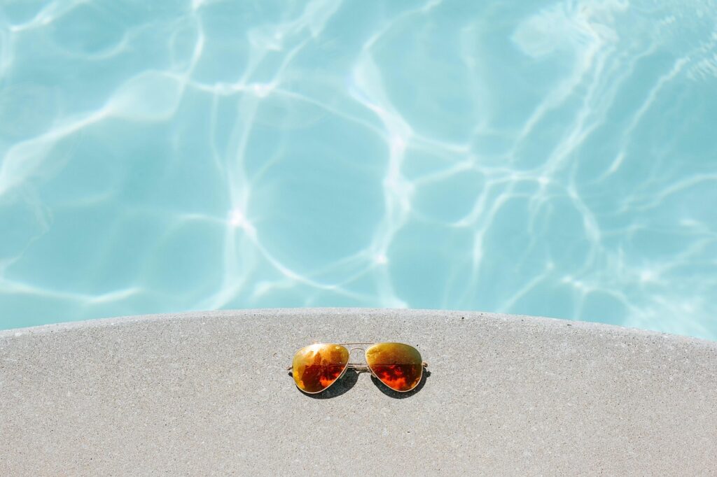 bordillo de piscina con unas gafas de espejo en naranja