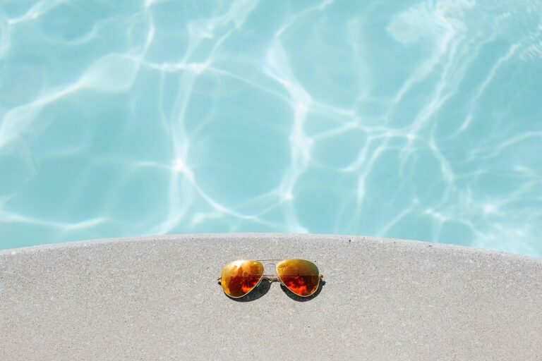 bordillo de piscina con unas gafas de espejo en naranja