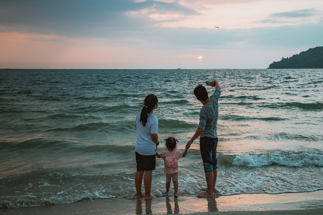 familia en la playa al atardecer que se hace un selfie