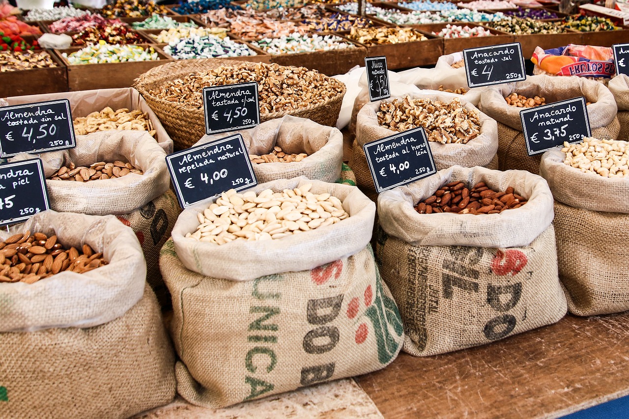 puesto de mercado donde se ven sacos abiertos con frutos secos y sus carteles con nombres y precios