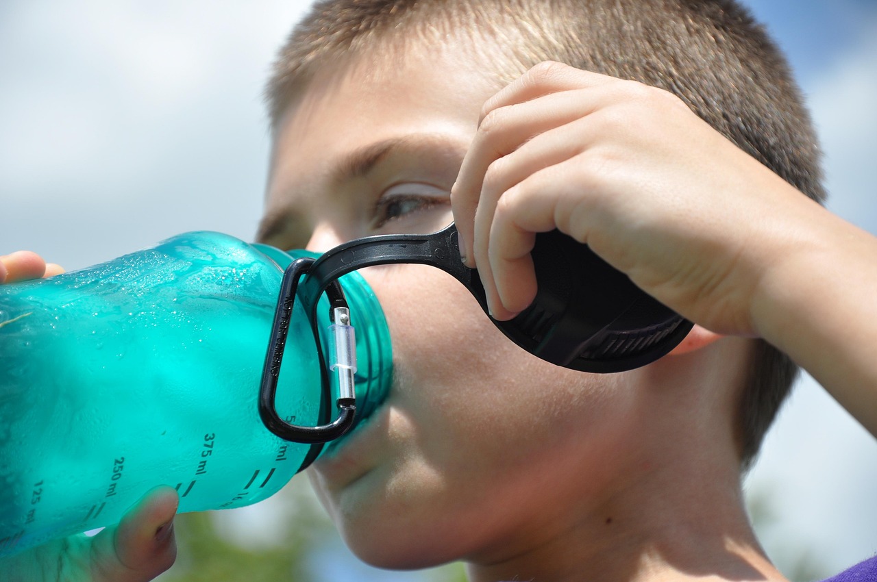 niño bebiendo de una botella de plástico azul