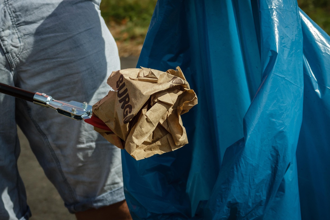 persona que recoge basura y la mete en una bolsa de basura azul