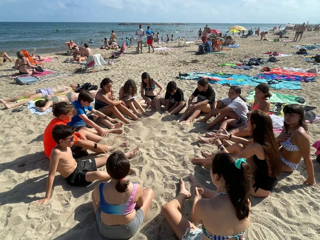 chicos y chicas sentados en corro en la playa