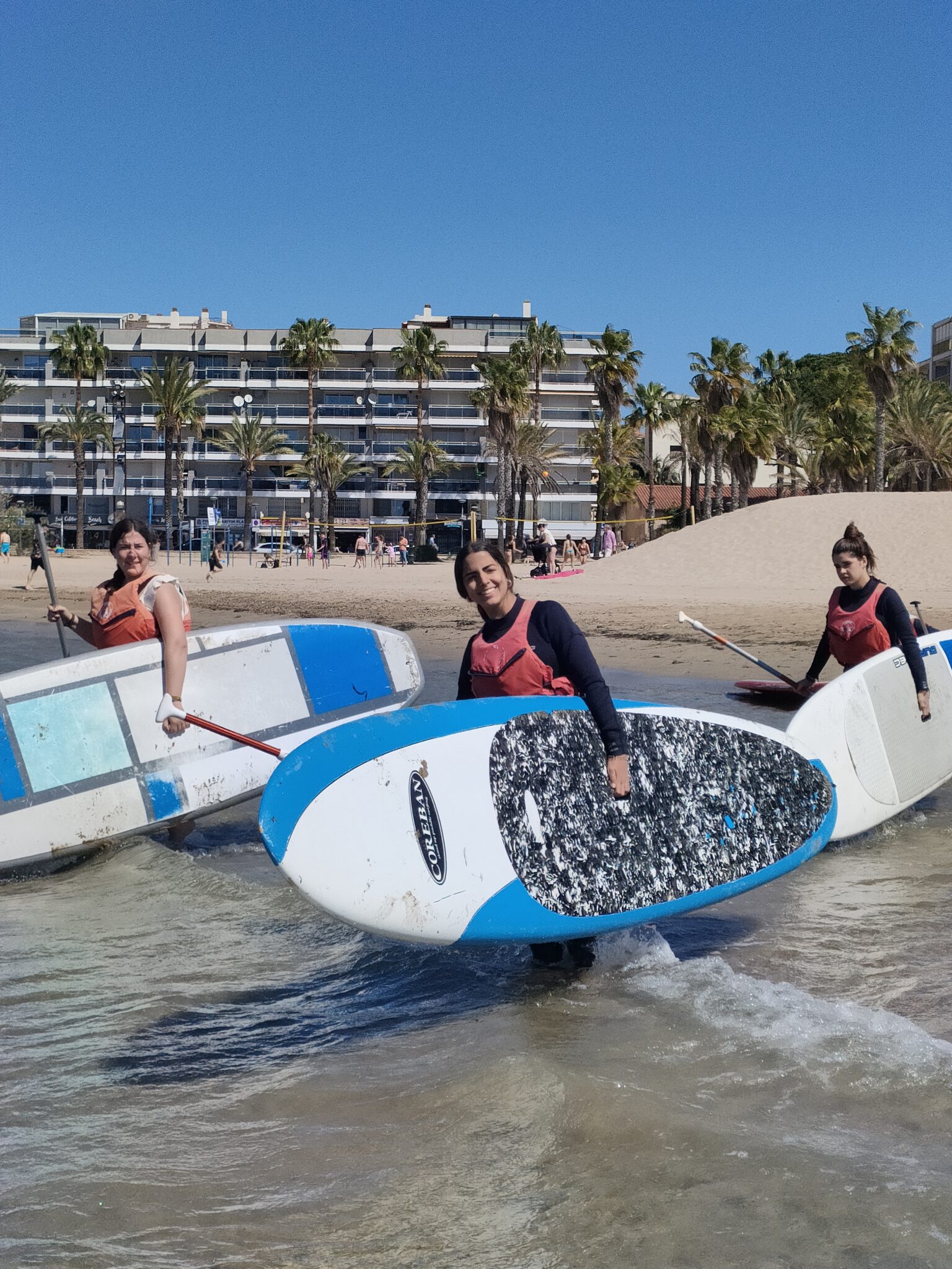 chicas con tablas de paddle surf entrando en el agua