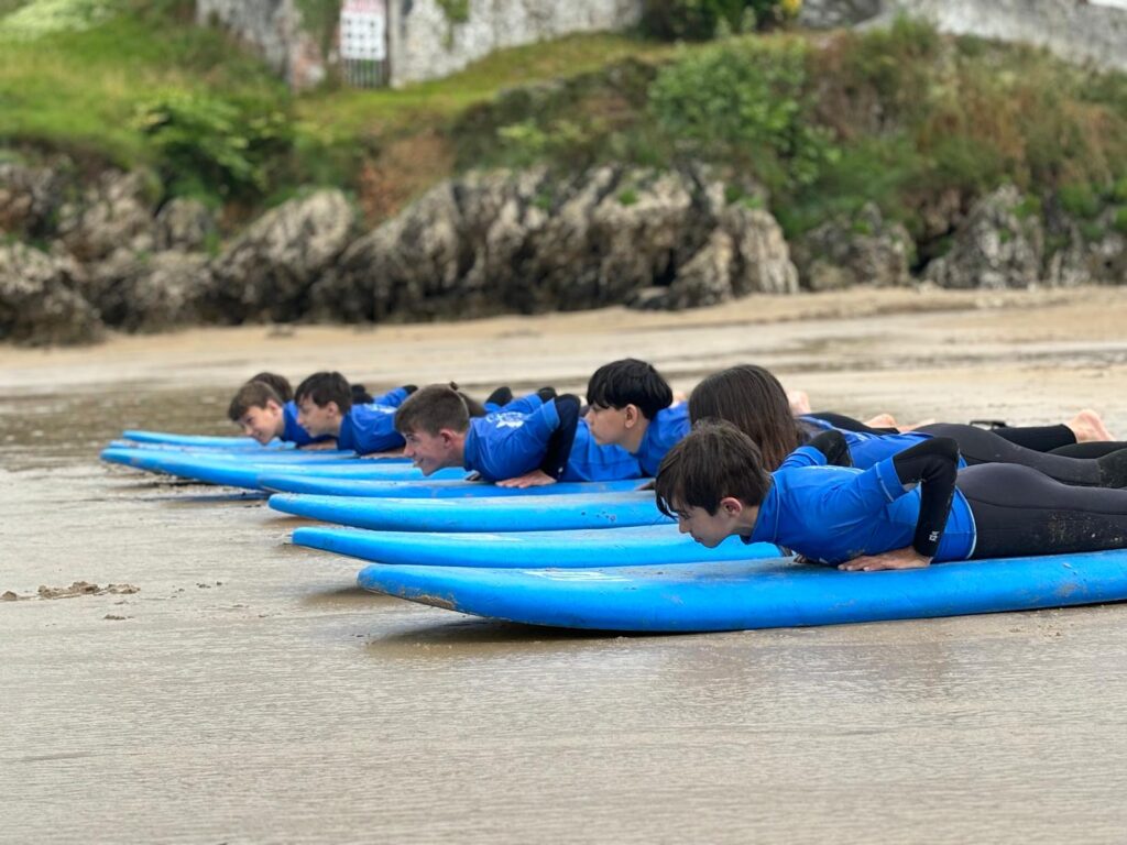 participantes tumbados en tablas de surf azul en la orilla del mar
