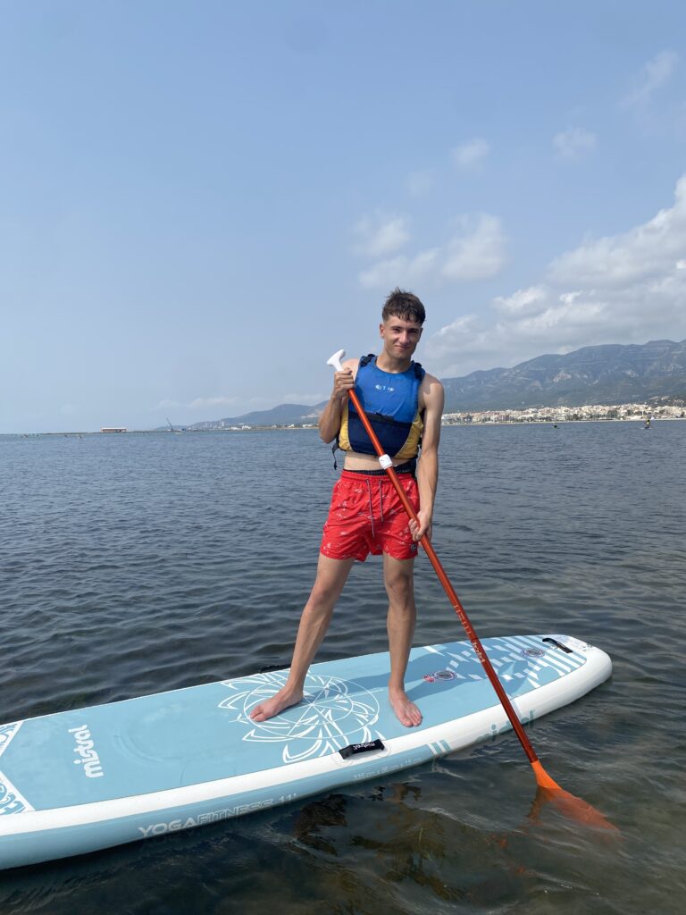 chaval encima de la tabla de paddle surf en medio del mar
