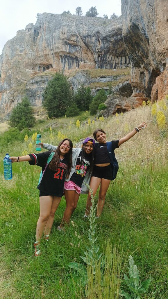 tres escolares en el campo con una montaña rocosa detrás